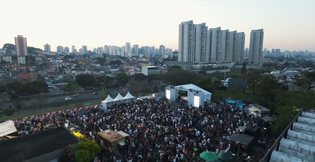 Vista aérea da área externa da ExpoCannabis Brasil, com o público reunido em frente ao palco ao entardecer