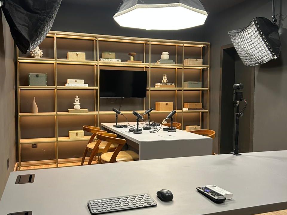 Bancada técnica do Estúdio B · M8, com a mesa de podcast e as luzes ao fundo