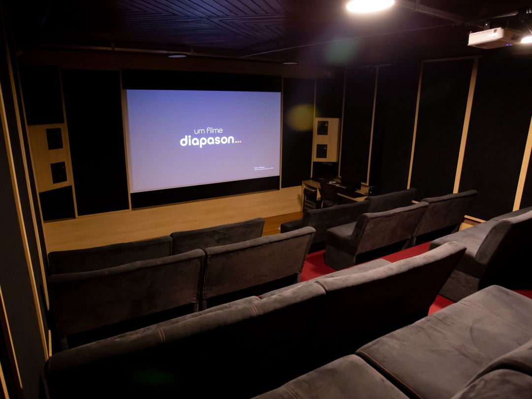 Sala de cinema do Estúdio A vista em ângulo, com a tela exibindo o logo da Diapason e luz dourada nas laterais