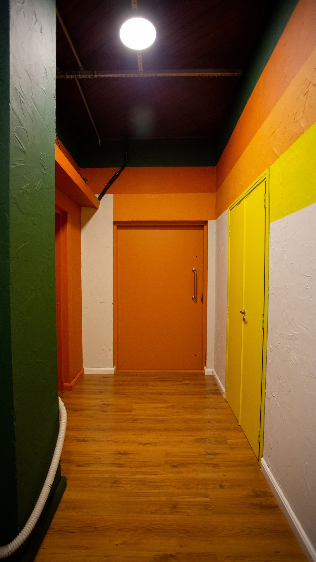 Corredor do Estúdio A com paredes verde, laranja e amarela levando às portas acústicas
