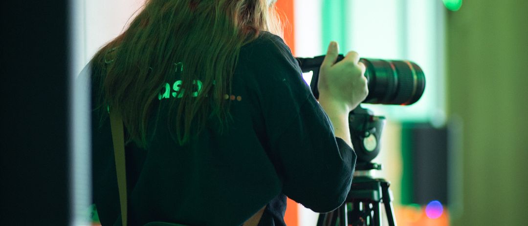 Cinegrafista da Diapason de costas, filmando sob luz verde num evento