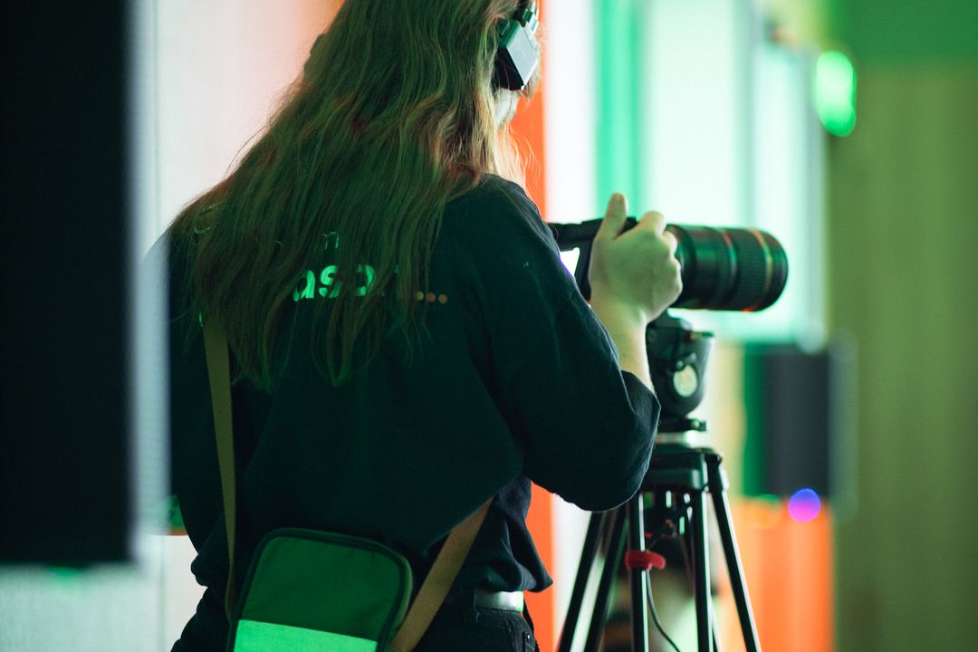 Cinegrafista da Diapason de costas, filmando sob luz verde num evento